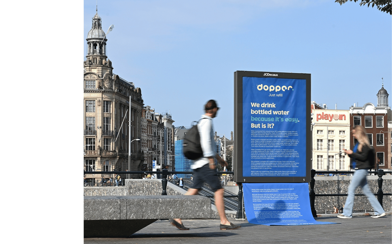 Two people walking in front of a blue ABRI campaign by Dopper
